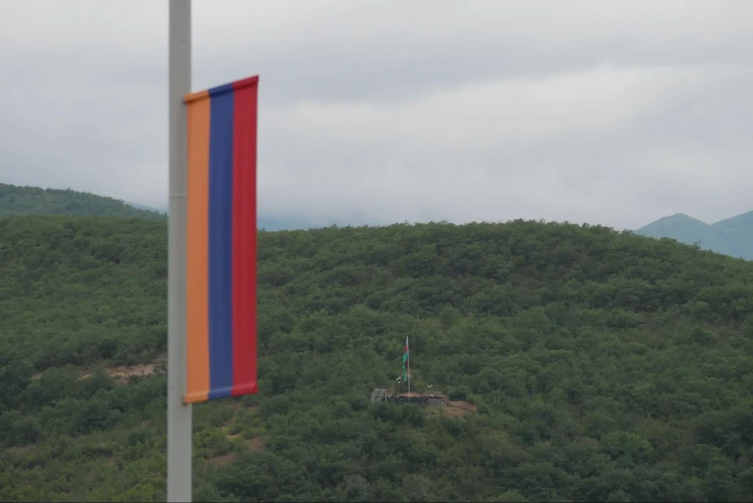 An Armenian flag and, in the distance, an Azerbaijani military position overlooking Kapan airport. The position appeared after Armenia’s 2020 defeat, when districts around Nagorno-Karabakh were handed to Azerbaijan. 📷 Karen Harutyunyan